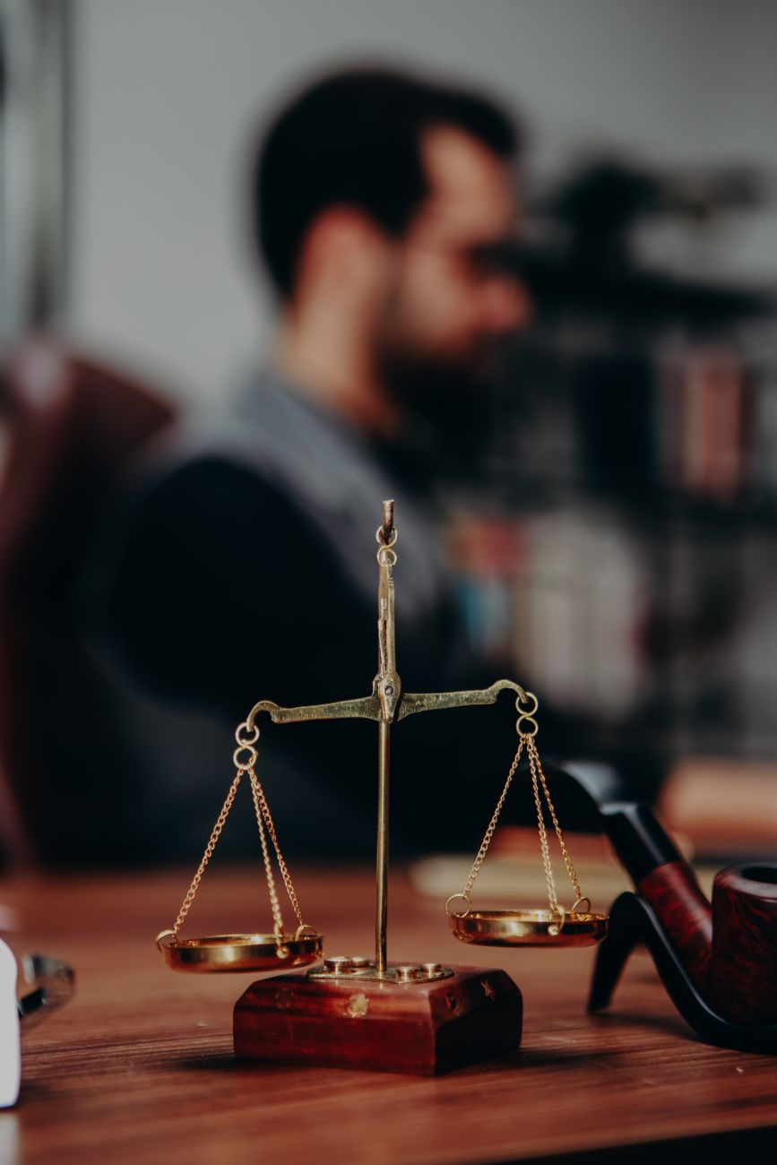 Balança da justiça sobre mesa com livros jurídicos